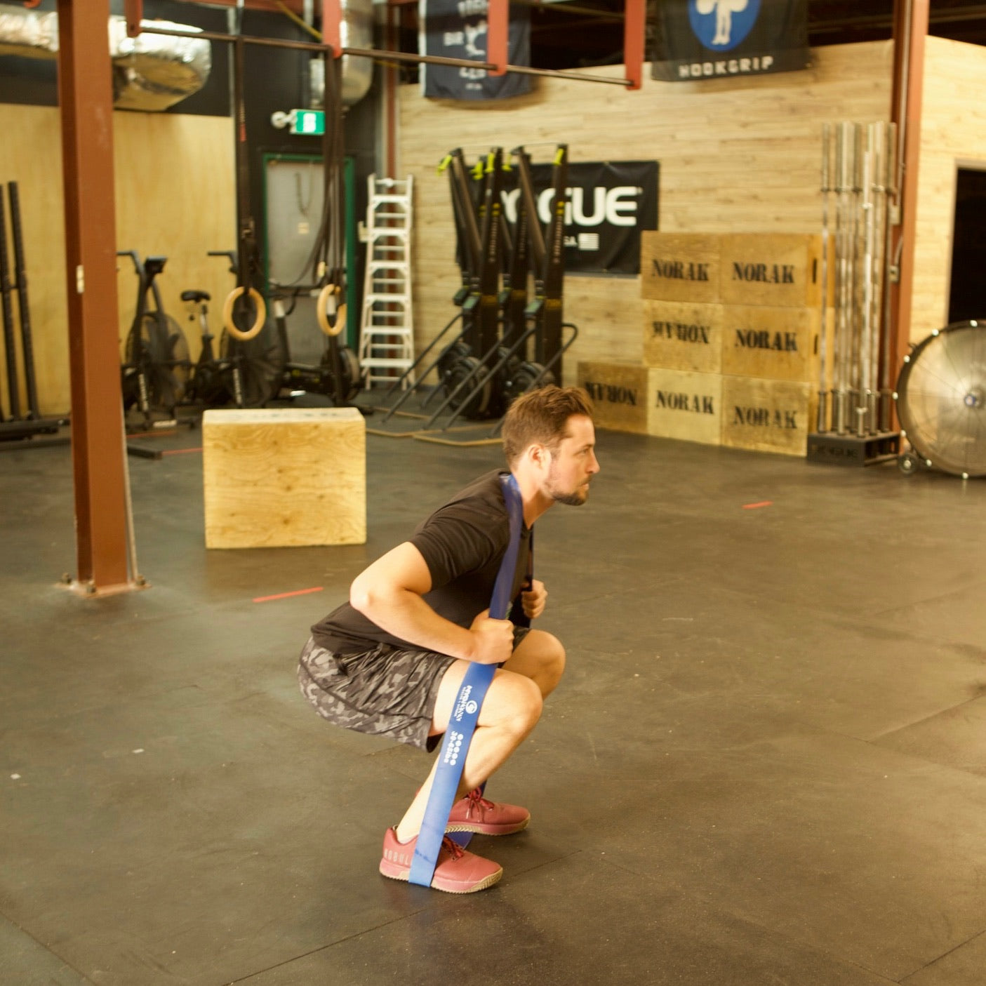 Man using heavy resistance exercise band to do squats and strengthen his legs